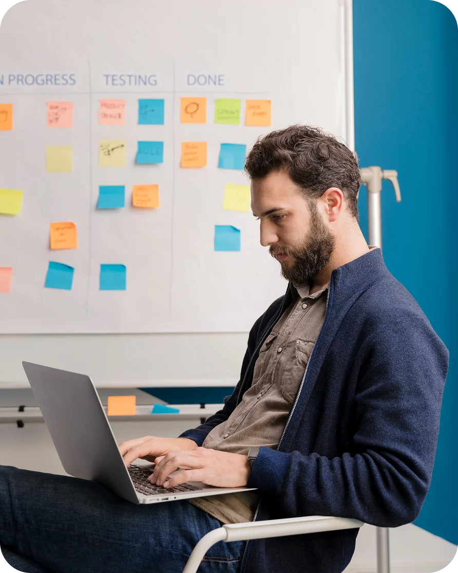 Bearded man working on a laptop, emphasizing quality assurance and testing.